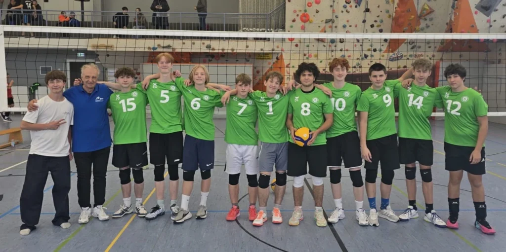 Die Aubing-Volleys stehen gemeinsam mit ihren Betreuern vor dem Volleyballnetz.